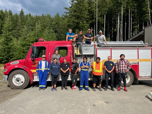 The 12 Ditidaht First Nation members standing in front of a fire truck with 2 FNESS staff