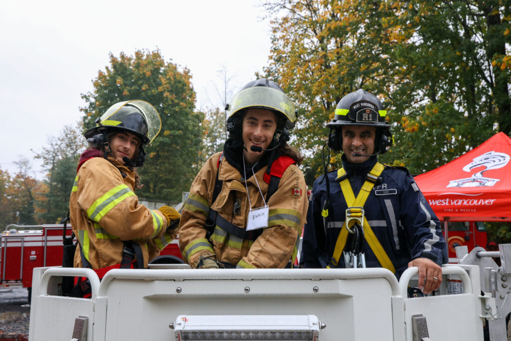 two youth in turn-out gear and with radio sets going up the tower with a firefighter