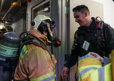 Fire services officer smiling making sure SCBA is on the student correctly.