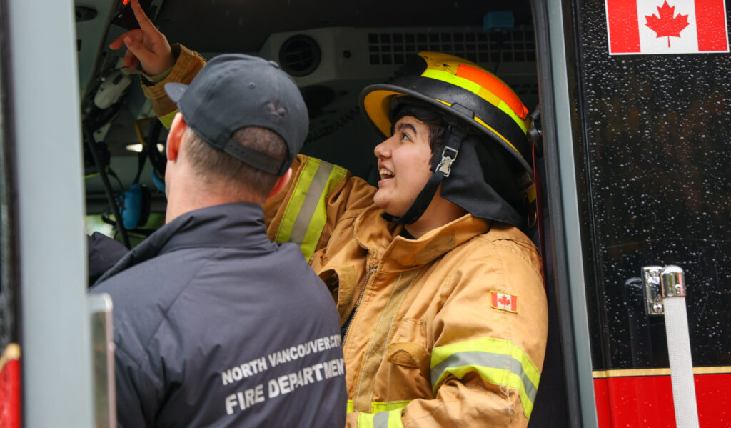 youth/student smiling as they sit in the drivers seat of fire engine.