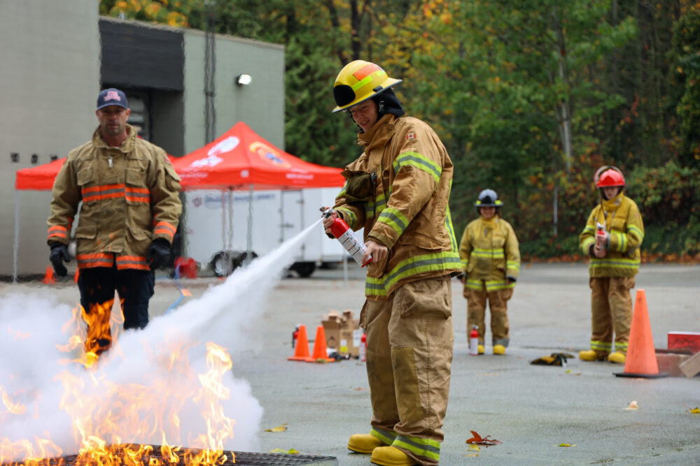 Youth in gear, putting out a staged fire with fire extinguisher