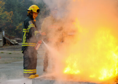 smiling youth student practicing fire extinguishers by putting out large staged fire.