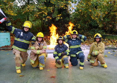 Youth firefighters celebrating after fire extinguisher practice.