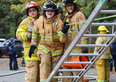 youth having fun learning how to use an extension ladder. they're laughing.