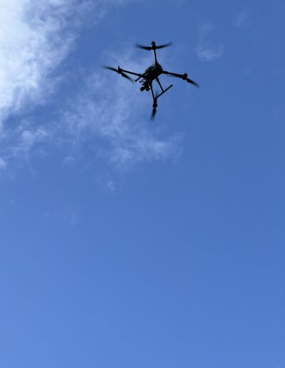 black drone flying high in the blue sky
